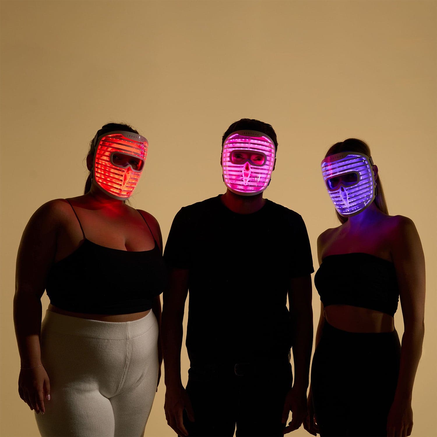 Three people wearing the exact iRestore Illumina face mask with different light modes illuminated.