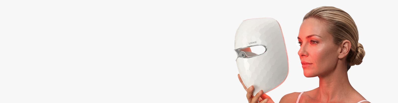 Woman holding the white Ulike ReGlow UM10 LED face mask in an official lifestyle image.